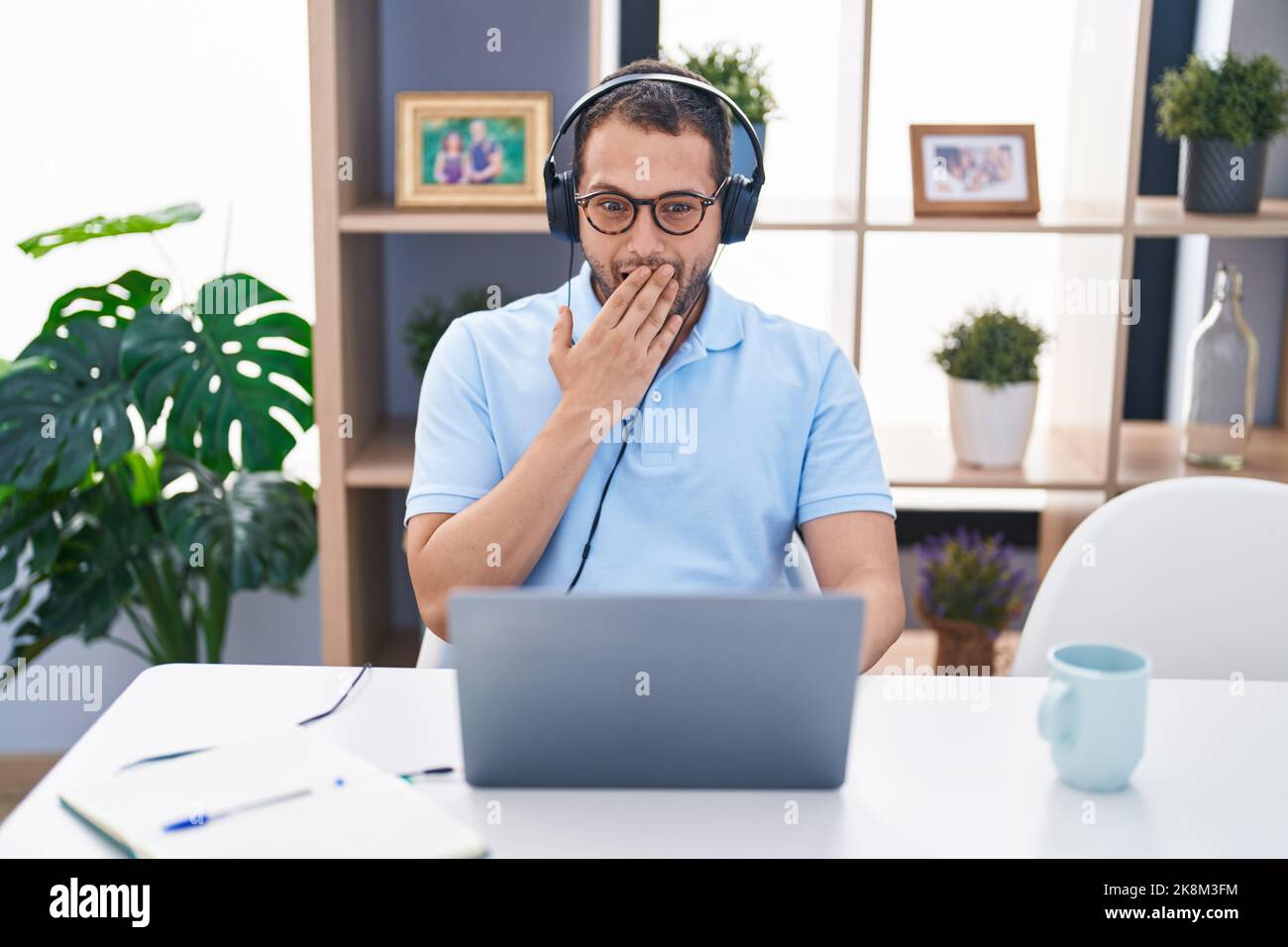 Hispanic man working using computer laptop wearing headphones covering ...