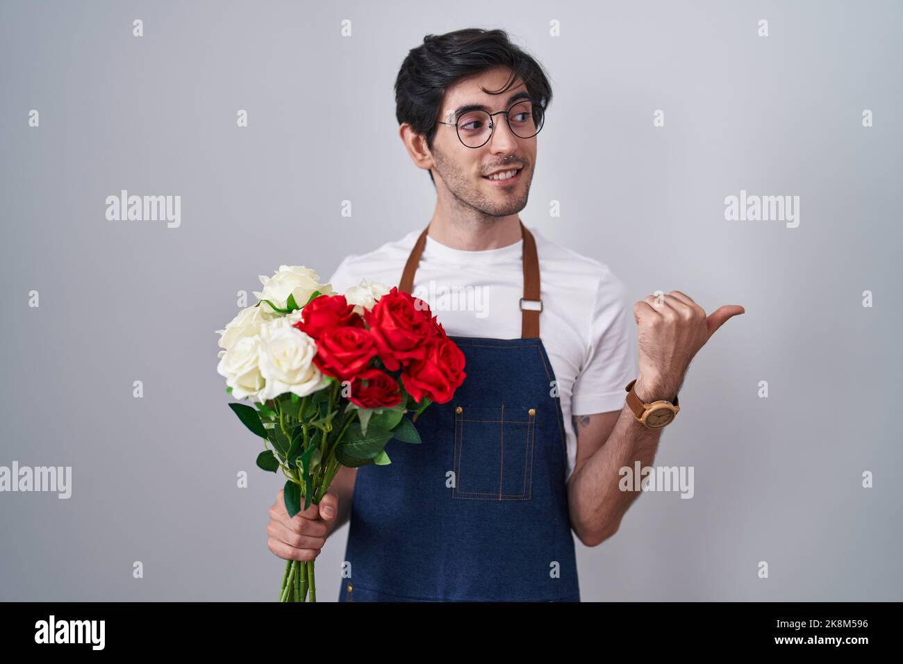 Young hispanic man holding bouquet of white and red roses smiling with ...
