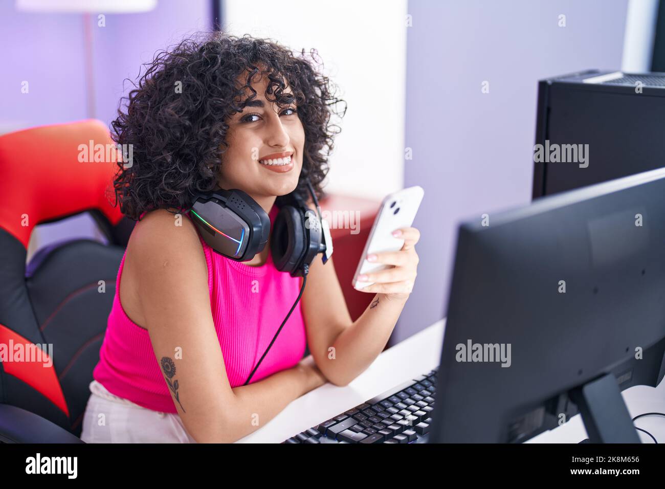 Young middle eastern woman streamer using computer and smartphone at