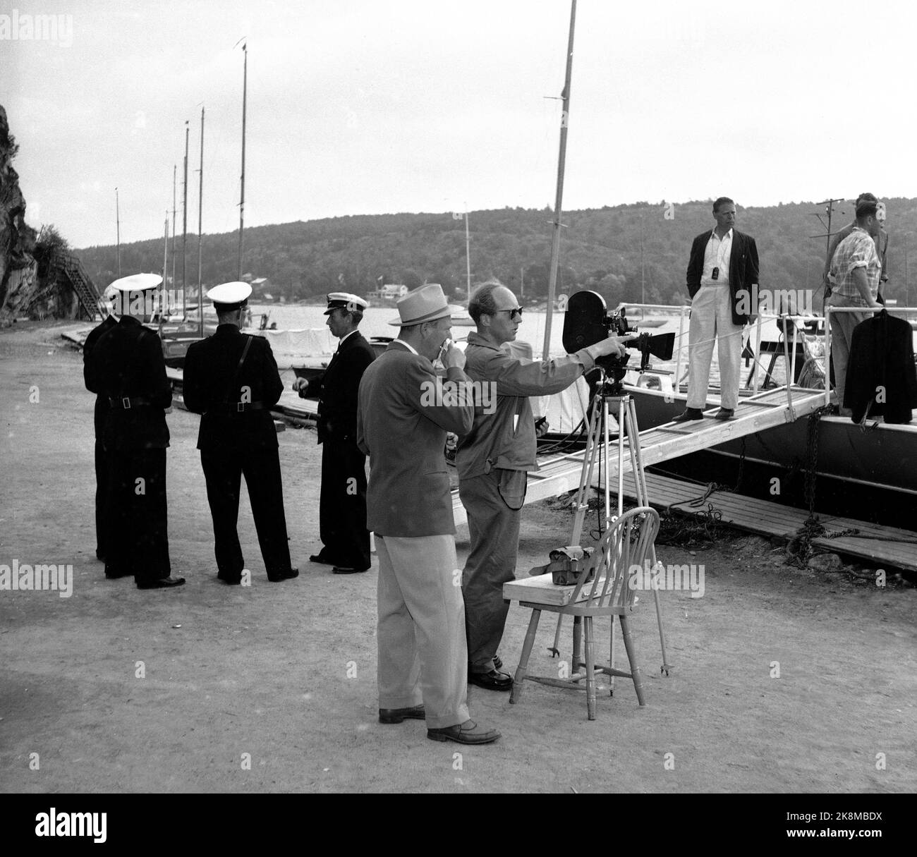 Hankø in the summer of 1956. Recording Norway's first feature film in color, titled "Smugglers in tuxedo". Here is a recording, the man with the sunglasses is probably photographer Finn Bergan? (or film photographer and clipper Per G. Jonson/Per Gunnar "Pege" Jonson). TV. Representatives of the police and customs authorities who have been at their disposal for the film recordings. Photo: Aage Storløkken / Current / NTB. Stock Photo