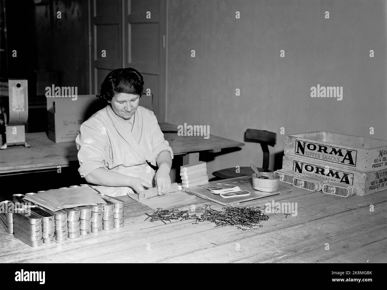 Stavanger 19510130 Working life at Norma canned factory in Stavanger. Woman in working to put keys on the canning boxes, as well as pack them in paper and put on the factory label. Boxes with Norma Logo Th. Photo: NTB / NTB Stock Photo