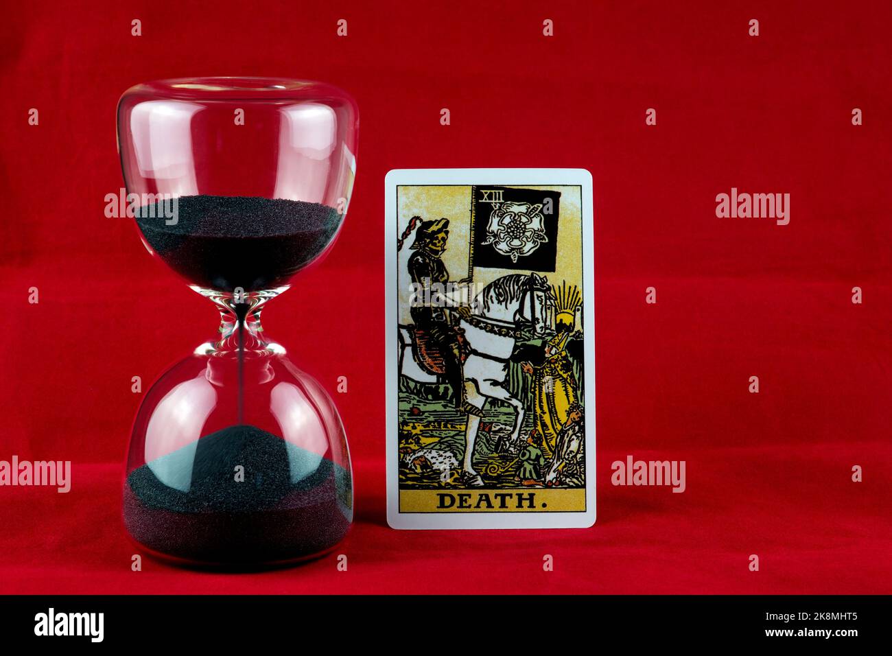 Death tarot card and hourglass on a red background Stock Photo