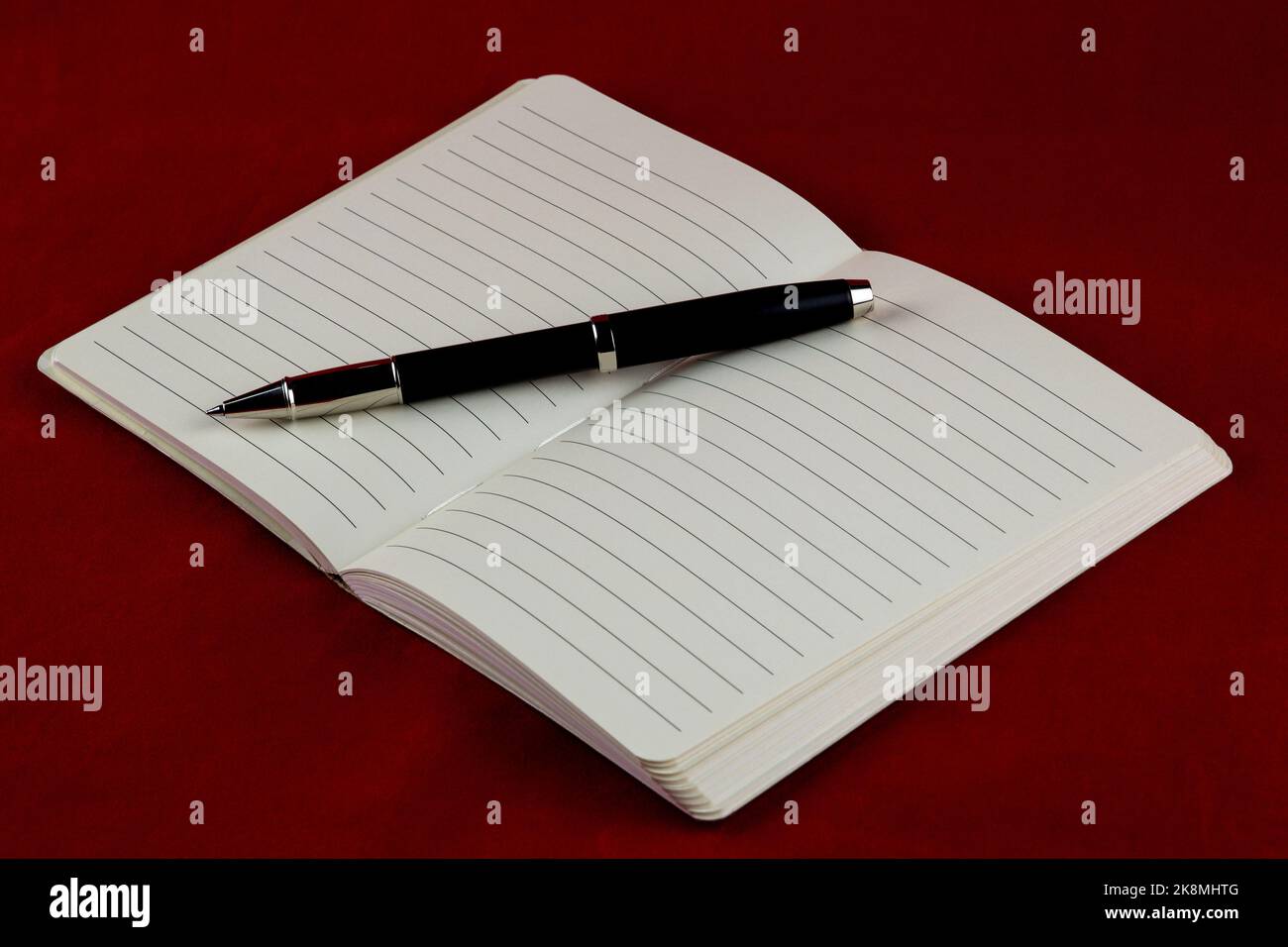 Rollerball pen and open notebook on a red table cloth Stock Photo