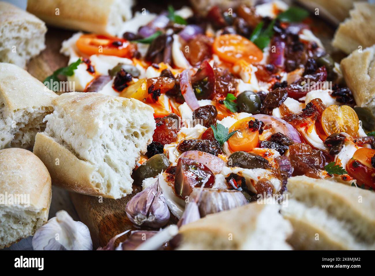 Butter board topped with red onions, roasted garlic cloves, kalamata