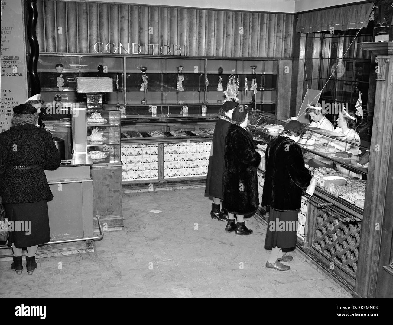 Oslo 19530201 Interior from Møllhausen Konditori in Karl Johans gate. Customers at the counter, female dispatchers with white aprons and caps behind the counter. Photo: NTB / NTB Stock Photo