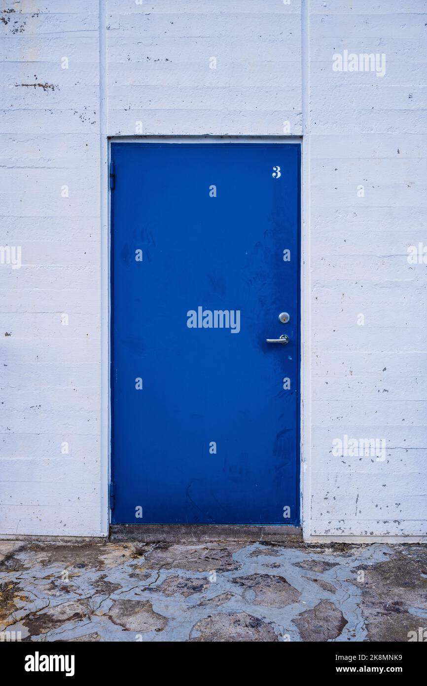 the blue metal door in the white concrete wall Stock Photo