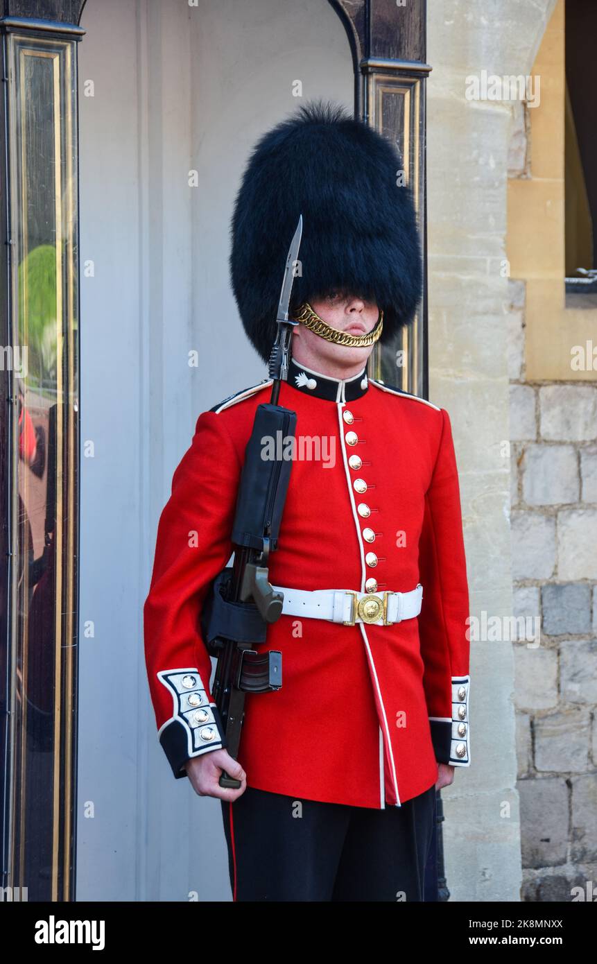 A vertical shot of a british guard carrying a weapon, with a red ...