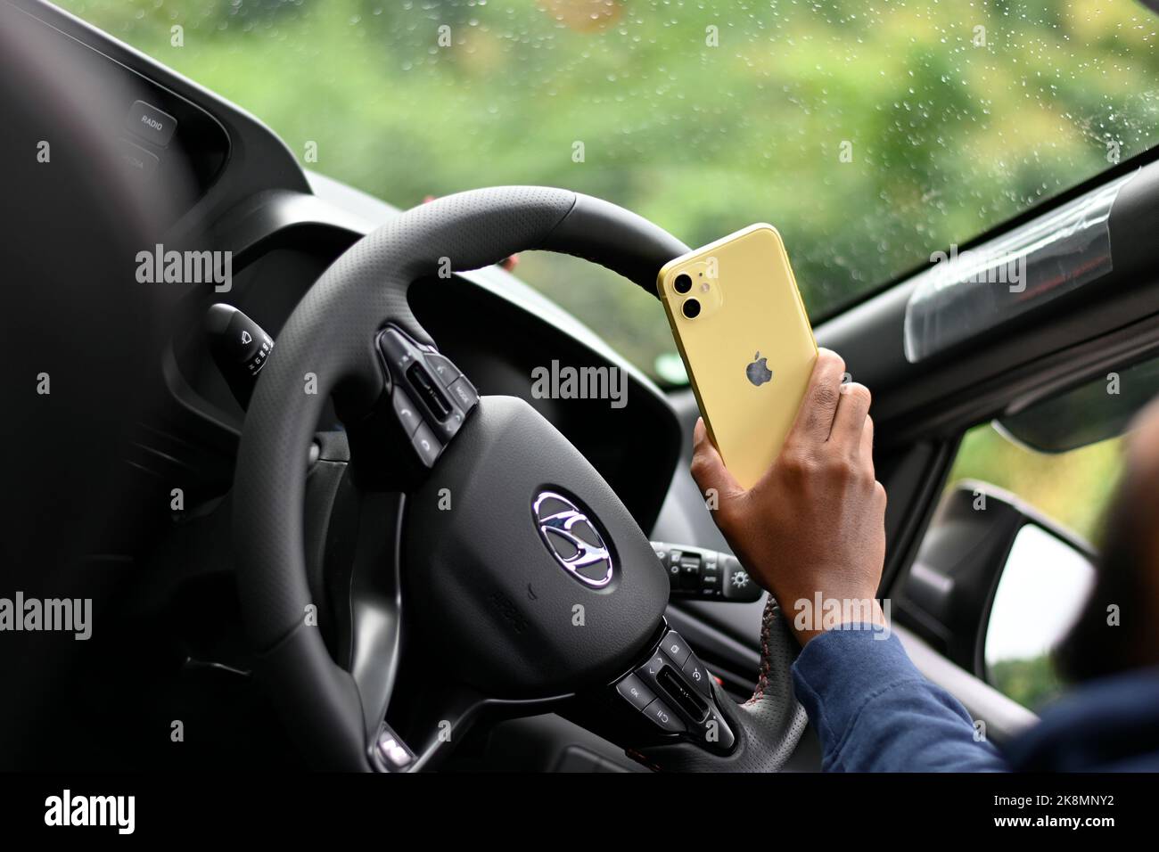 An iPhone mobile in a human's hand sitting in Hyundai car Stock Photo