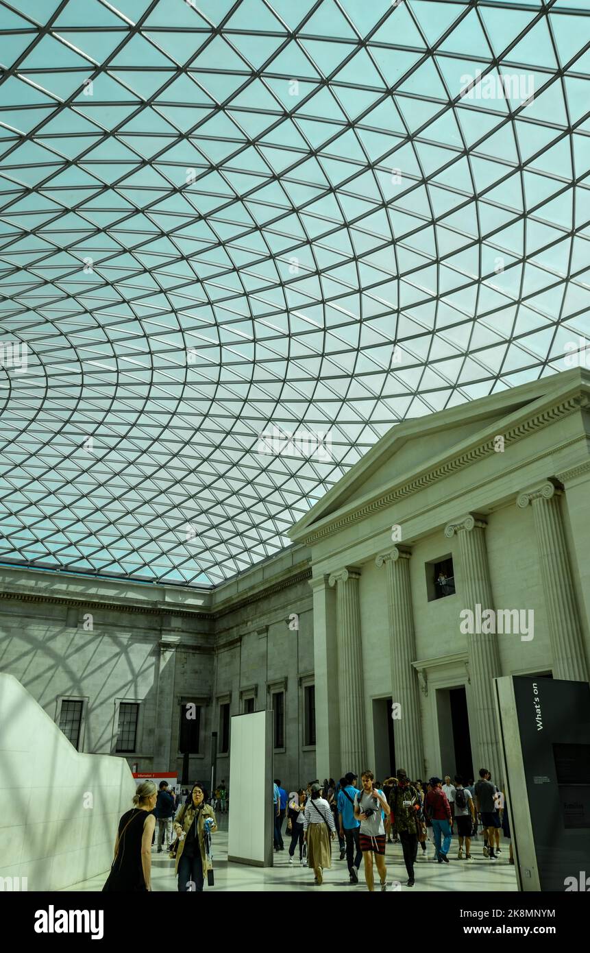 A vertical shot of the Great Court building in the British Museum ceiling with people walking around. Stock Photo