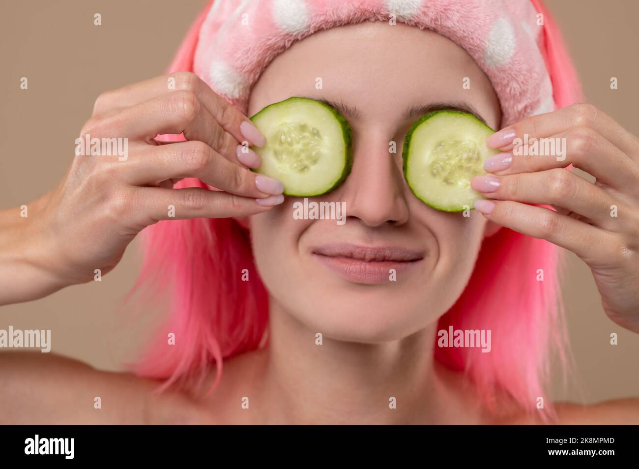 Smiling young girl using cucumber for face care Stock Photo