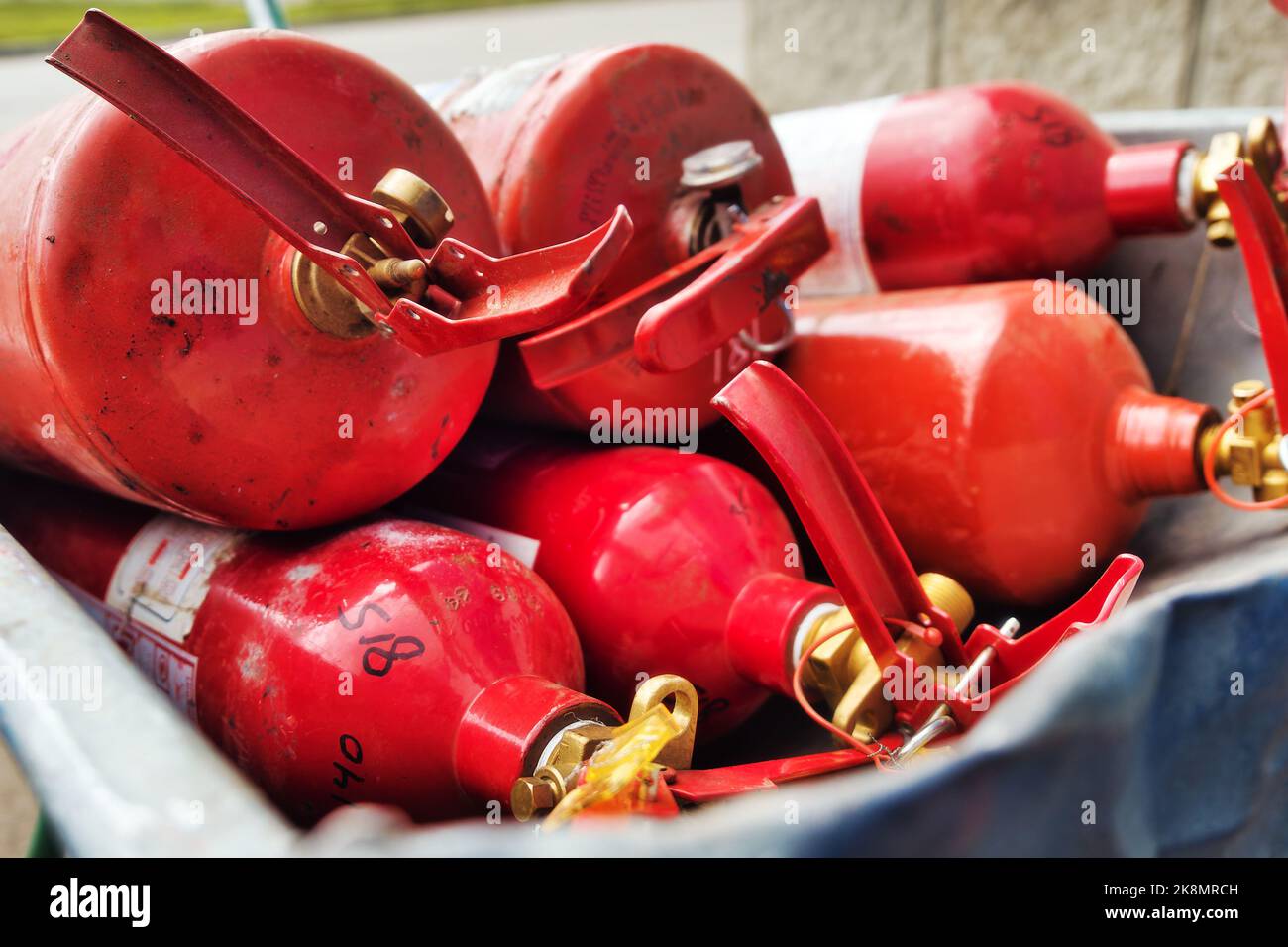 Many red fire extinguishers are lying in stack. Fire extinguishing equipment. Distribution of fire extinguishers for extinguishing fires.. Stock Photo