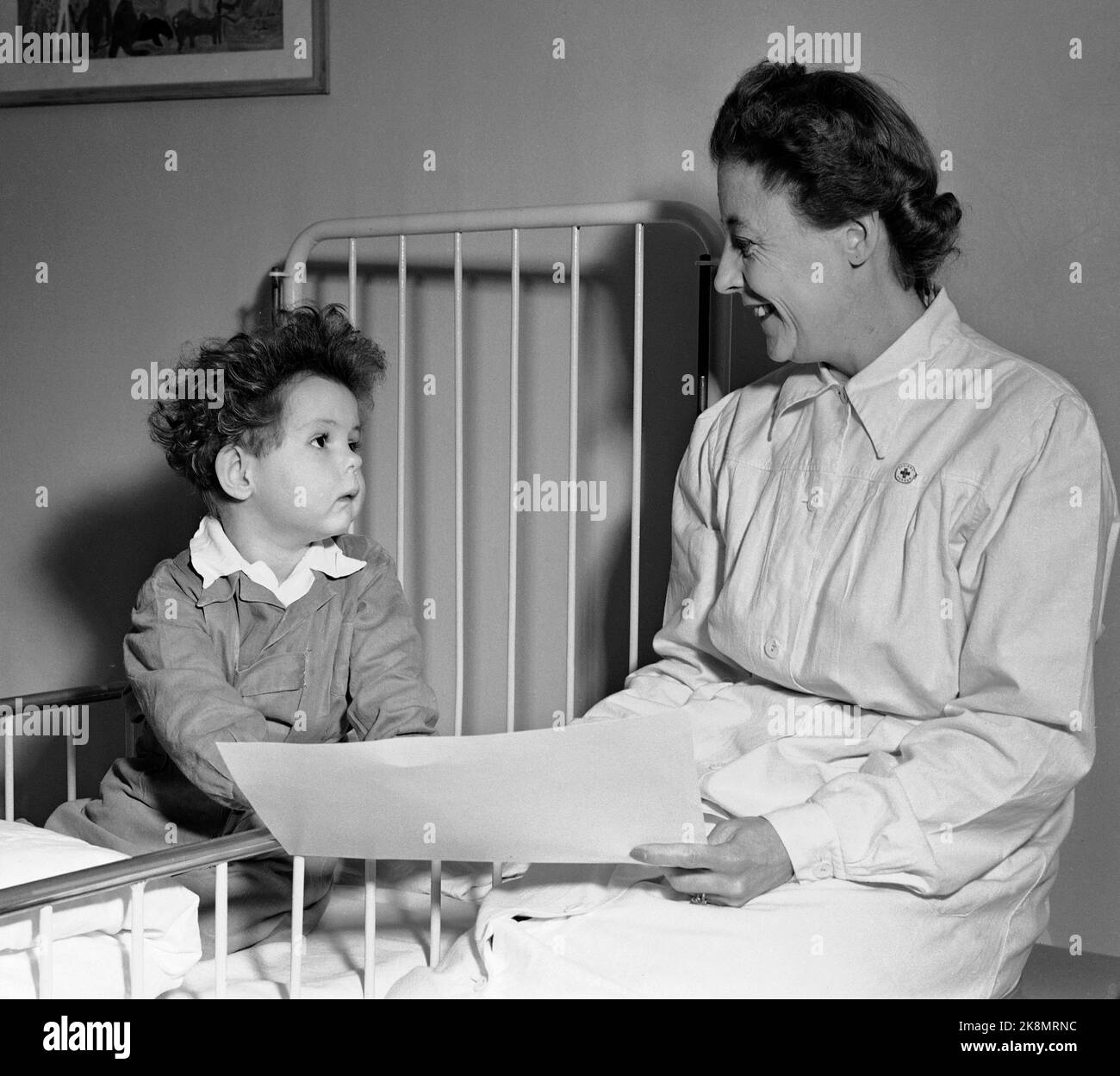Oslo 19520301 In 1948, the Norwegian Red Cross took the initiative for training patient friends, volunteers who could visit lonely in hospitals or in the homes. The scheme was put into life in 1949. Here a female patient friend who visits a small child in hospital. The visit was welcome, at a time when it was not common to have mother and father in the hospital. Photo: NTB / NTB Stock Photo