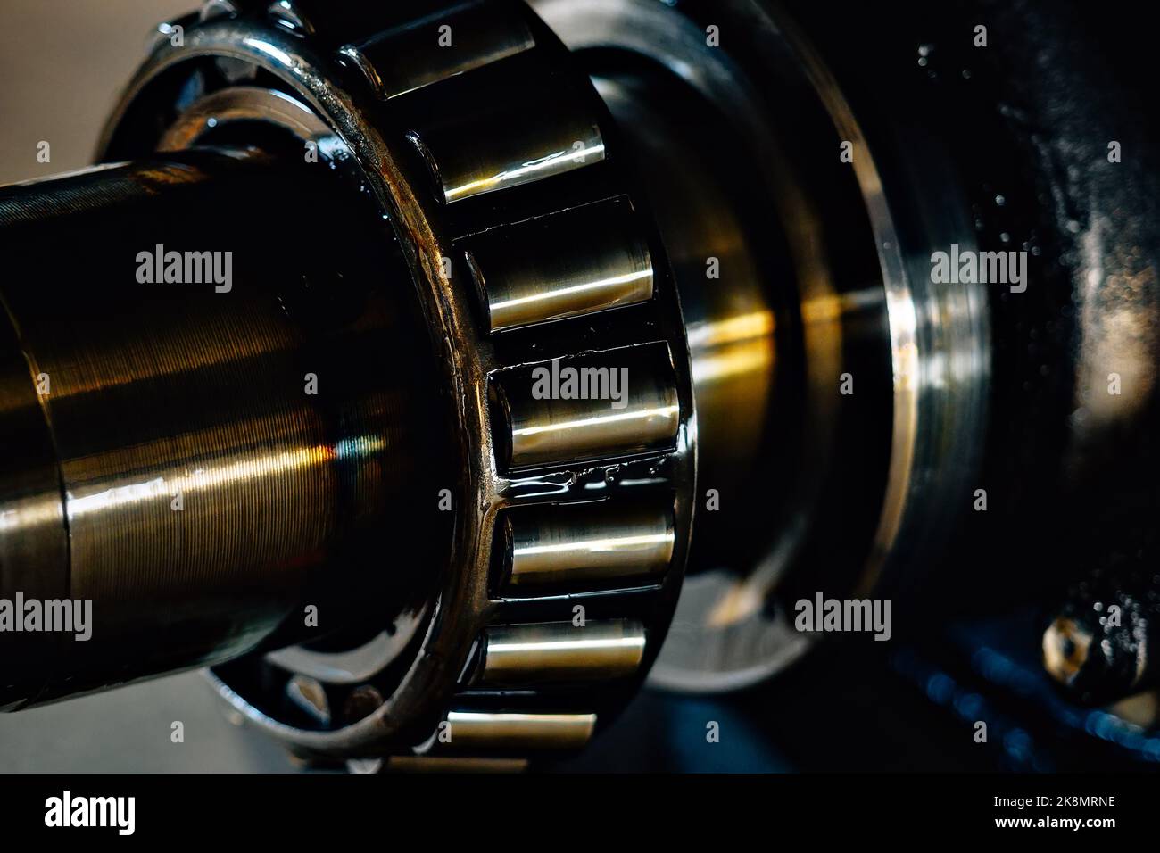 Closeup of a tapered roller bearing in grease on a dark industrial