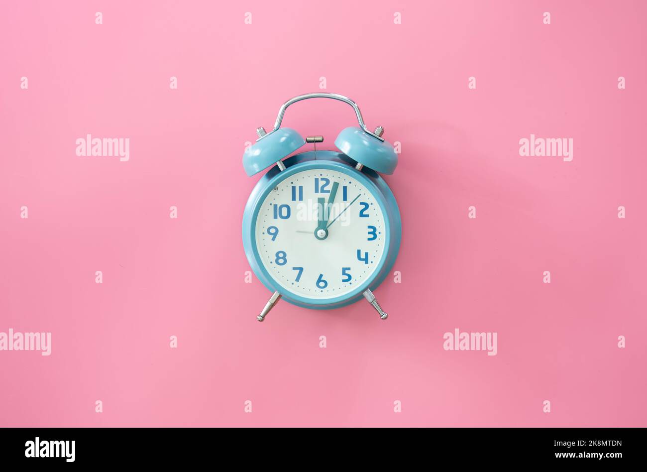 Blue alarm clock on a pink background isolated Stock Photo - Alamy