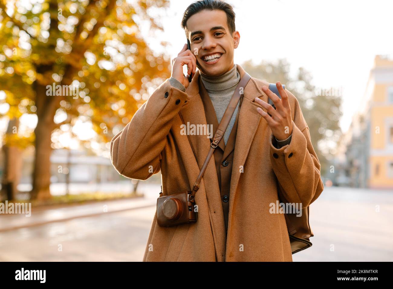 Young man gesturing while talking on mobile phone in park outdoors Stock Photo