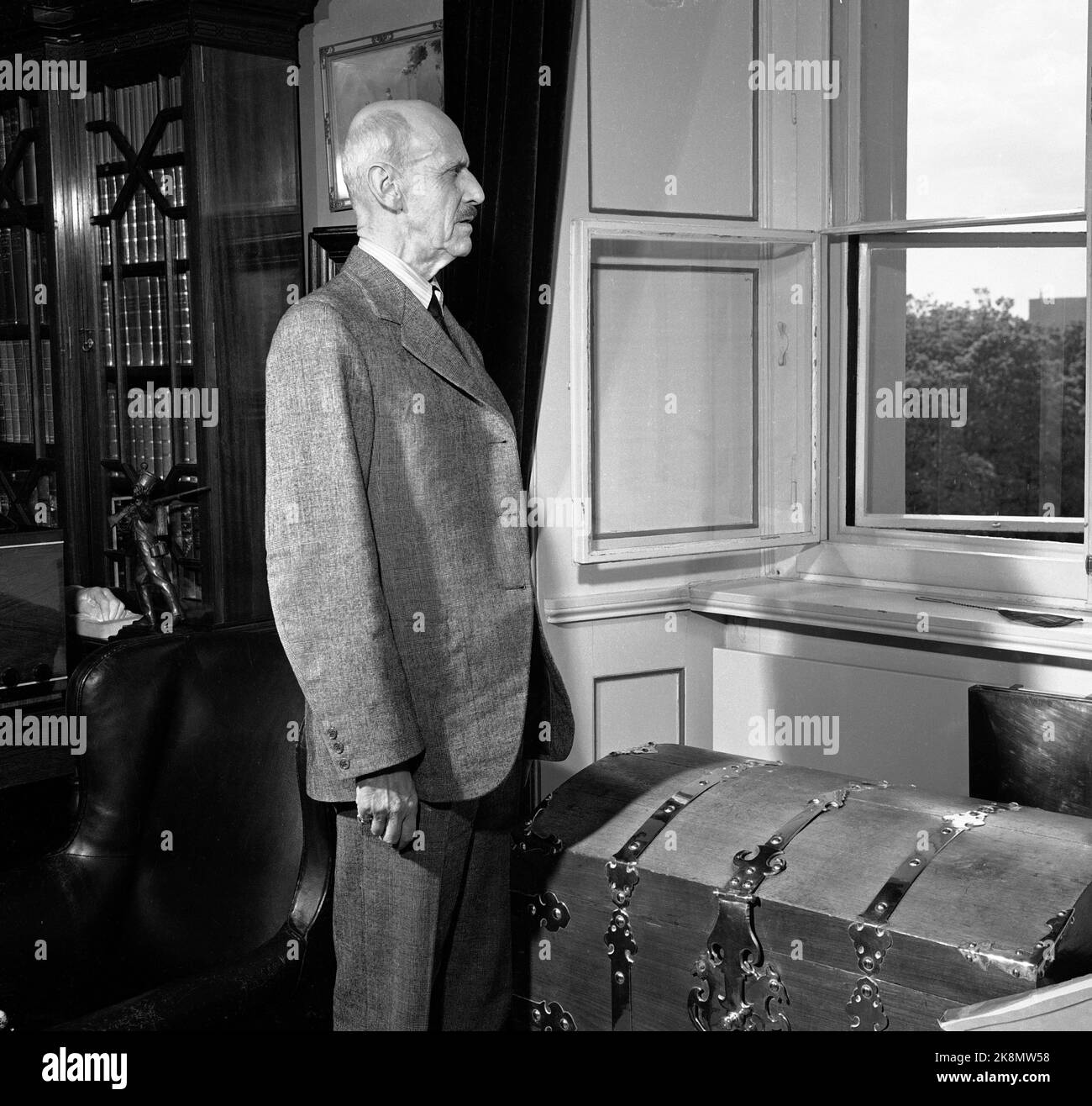 Oslo 19510526: King Haakon VII photographed at the castle. The king stands and looks out the window out to the castle square. Photo: NTB / NTB Stock Photo