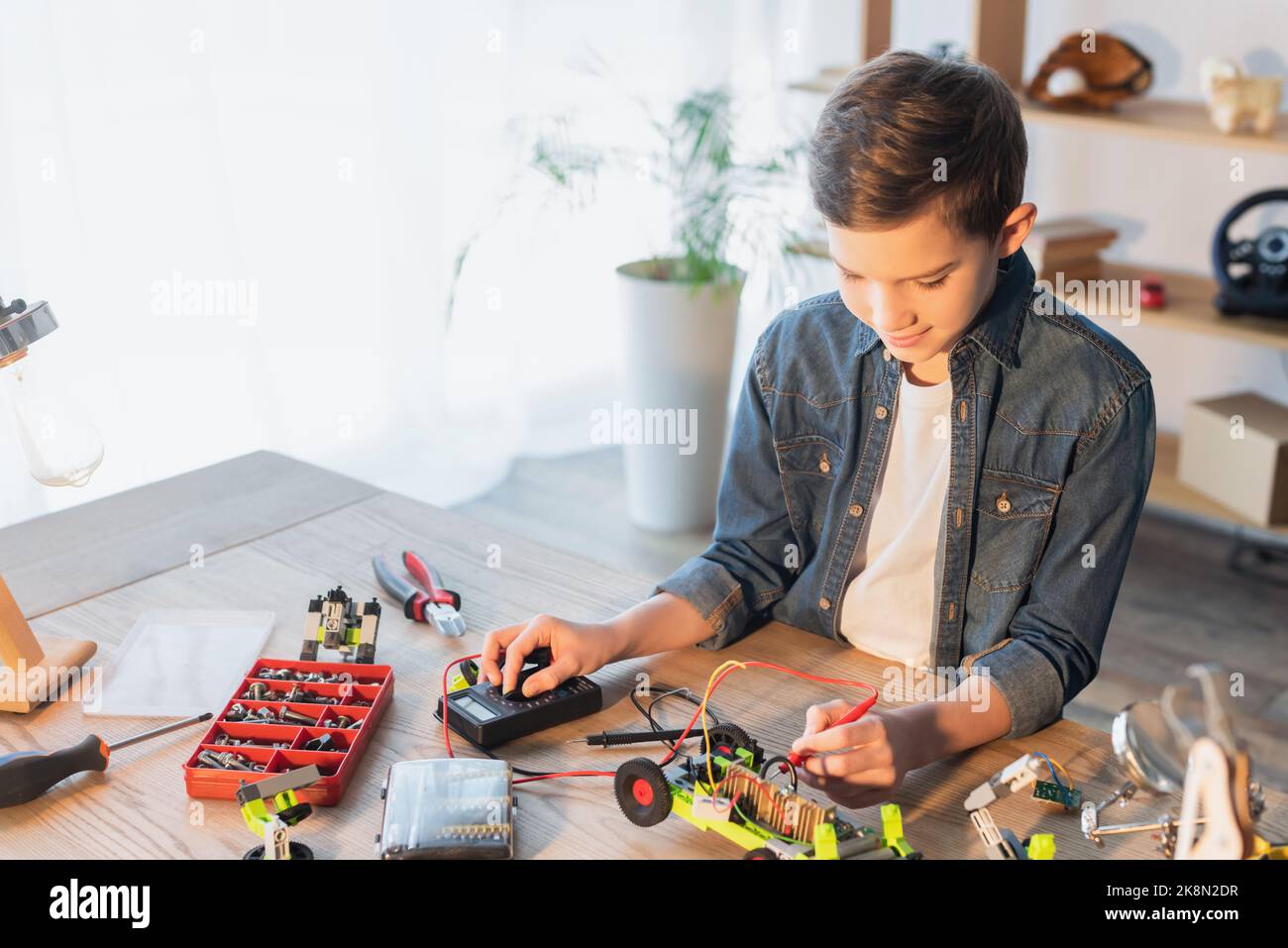 Preteen boy making robotic model with millimeter near tools and screws at home,stock image Stock Photo