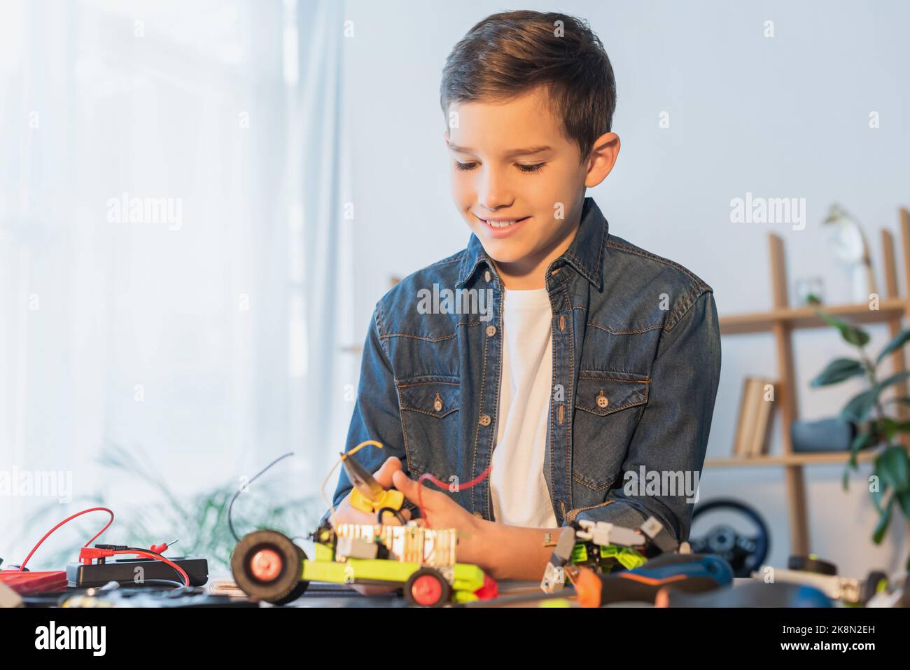 preteen boy with pliers assembling robotics model on table at home,stock image Stock Photo