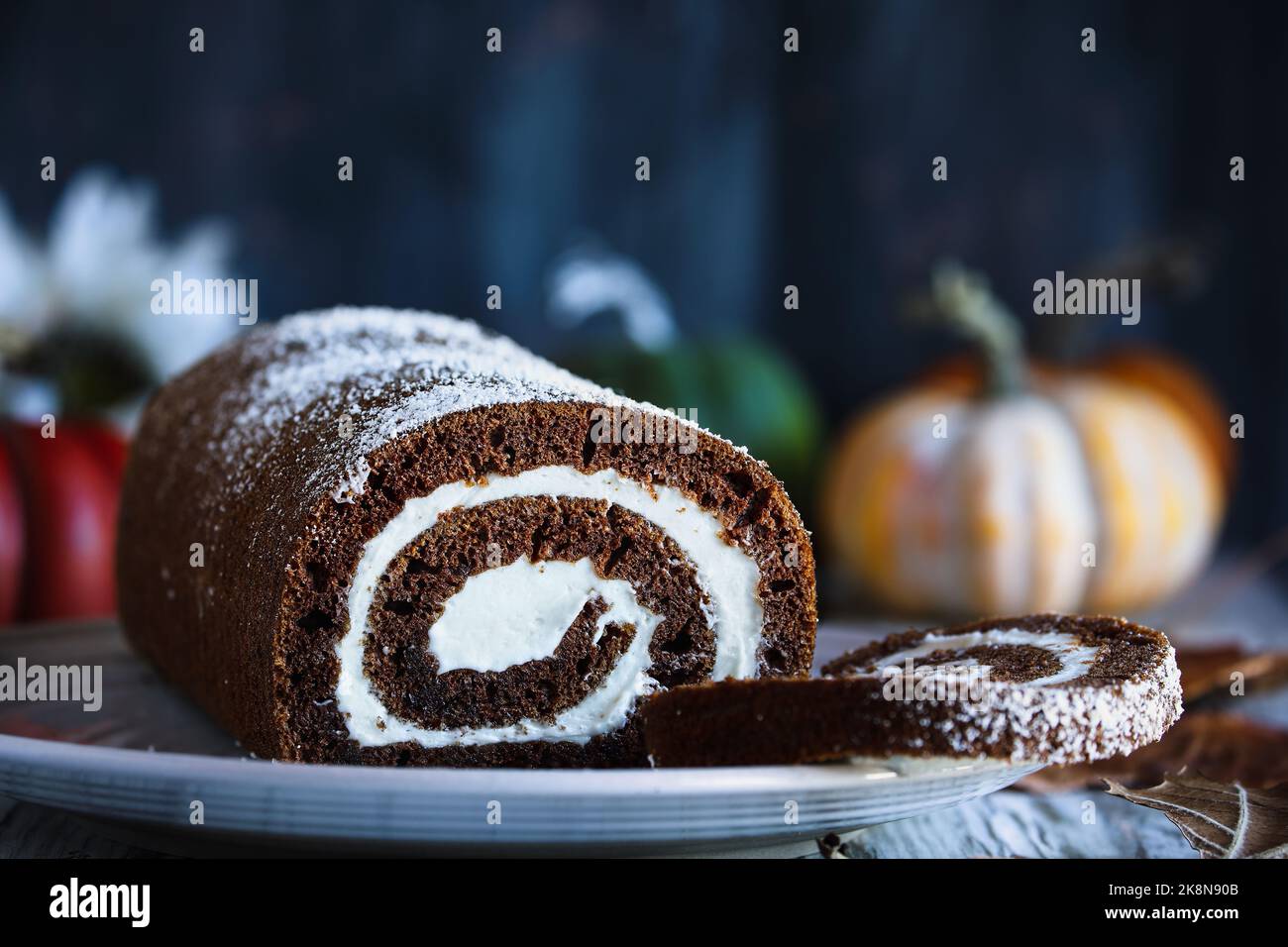 Fresh baked round chocolate pumpkin roll cake with powdered sugar and cream cheese filling. Selective focus with blurred foreground background. Stock Photo
