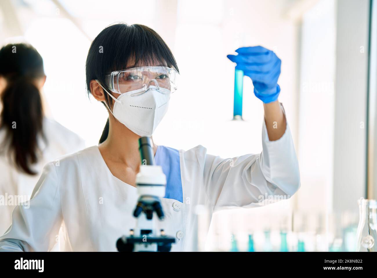 Female scientist looking at liquid in test tubes working in modern