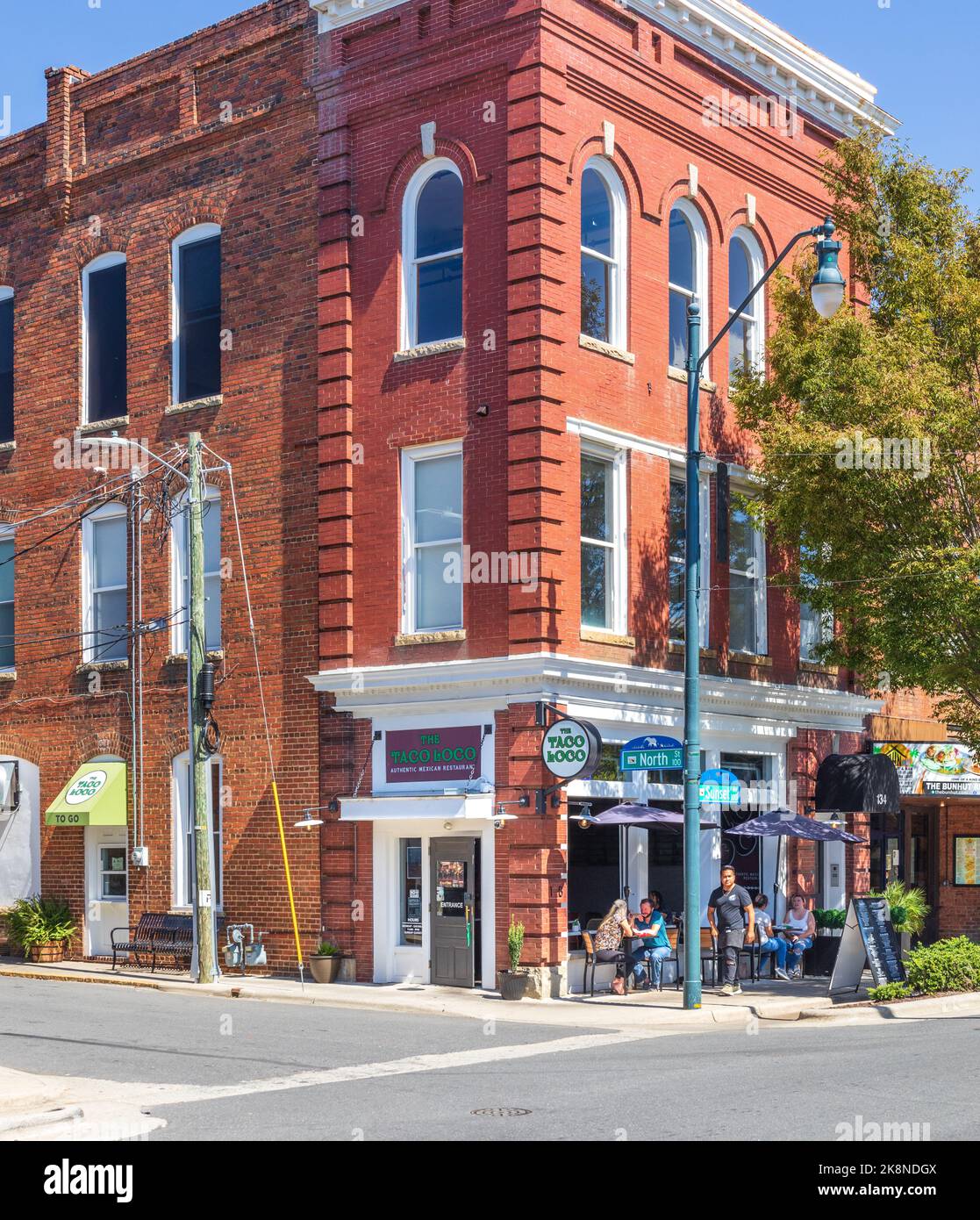 ASHEBORO, NC, USA-26 SEPT 2022: Street corner view of historic building hosing the Taco Loco, showing people seated on sidewalk. Stock Photo
