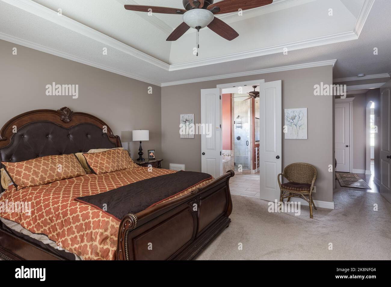 A large expensive bedroom with a double wooden bed, grey walls and