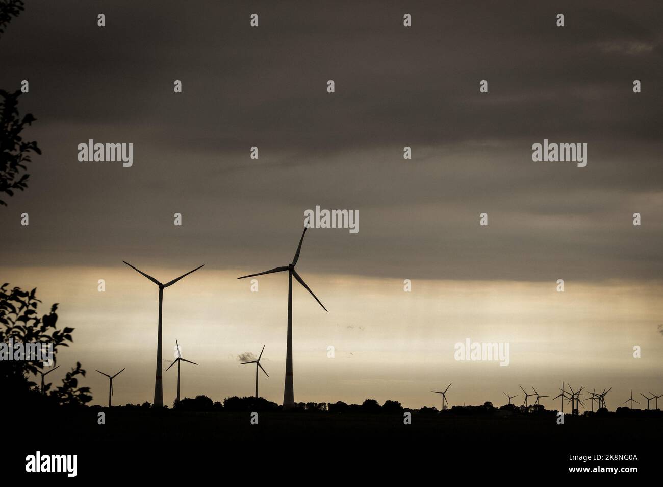 Some silhouettes of wind turbines at sunset, cloudy and dusty sky ...