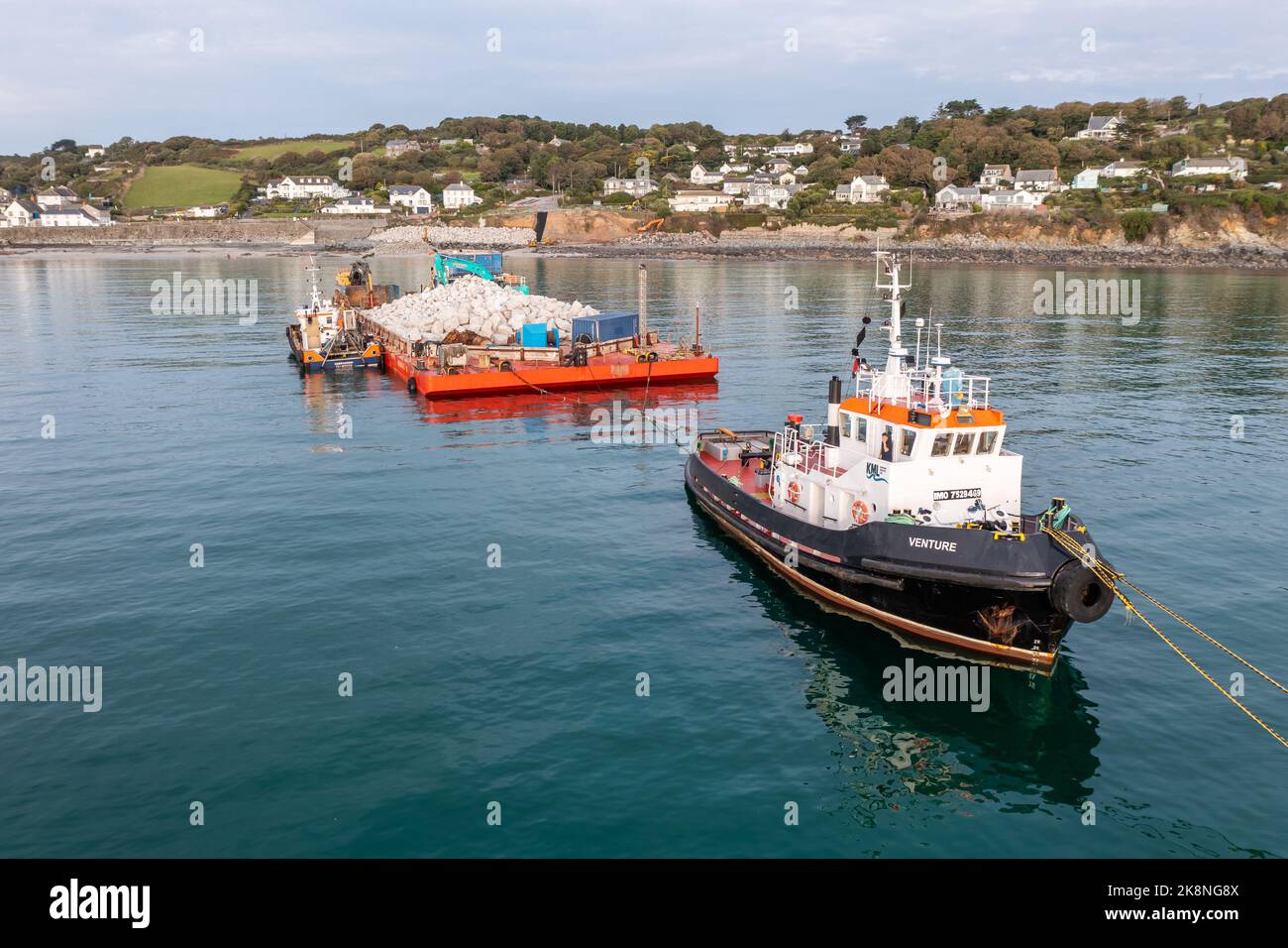 COVERACK, UK - SEPTEMBER 20, 2022.  A nautical tugboat and barge delivering quarried stone to enable the repair of the sea defences in Coverack, Cornw Stock Photo