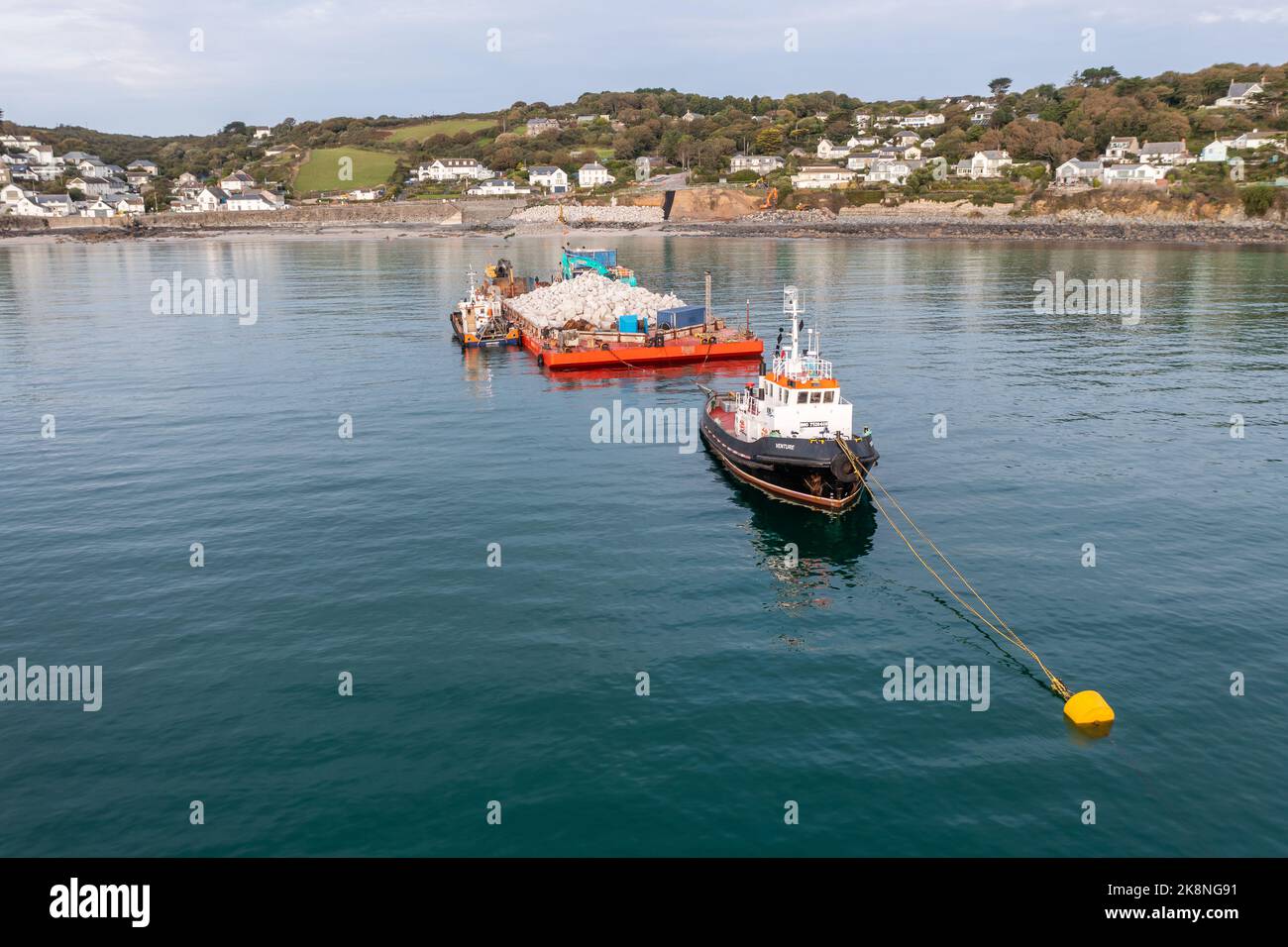 COVERACK, UK - SEPTEMBER 20, 2022.  A nautical tugboat and barge delivering quarried stone to enable the repair of the sea defences in Coverack, Cornw Stock Photo
