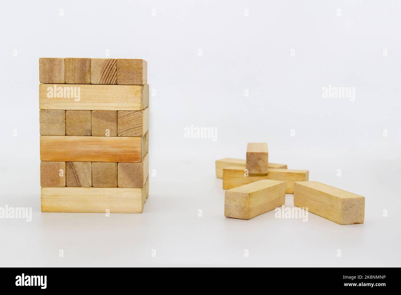 Tower wooden block, builds tower from wooden blocks against white background. The wooden bricks lying around randomly Stock Photo