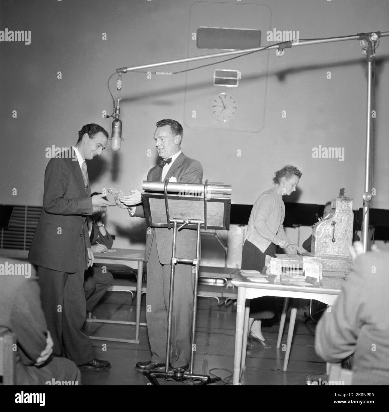 Oslo 19541209 from NRK's radio program 'The light hour' where the knowledge competition 'The question' with Rolf Kirkvaag was included. The cash register 'Jonatan' was central to the program. The questions had to be found on the questions, they were divided into five groups after free elections. Five kroner for the first straight, rising to eighty shiny kroner if you answered all the questions correctly, it was the concept behind 'the question'. Here Rolf Kirkvaag (in the middle) asks the question, while an assistant awaits the cash register Jonatan to pay any gain. Photo: NTB / NTB Stock Photo