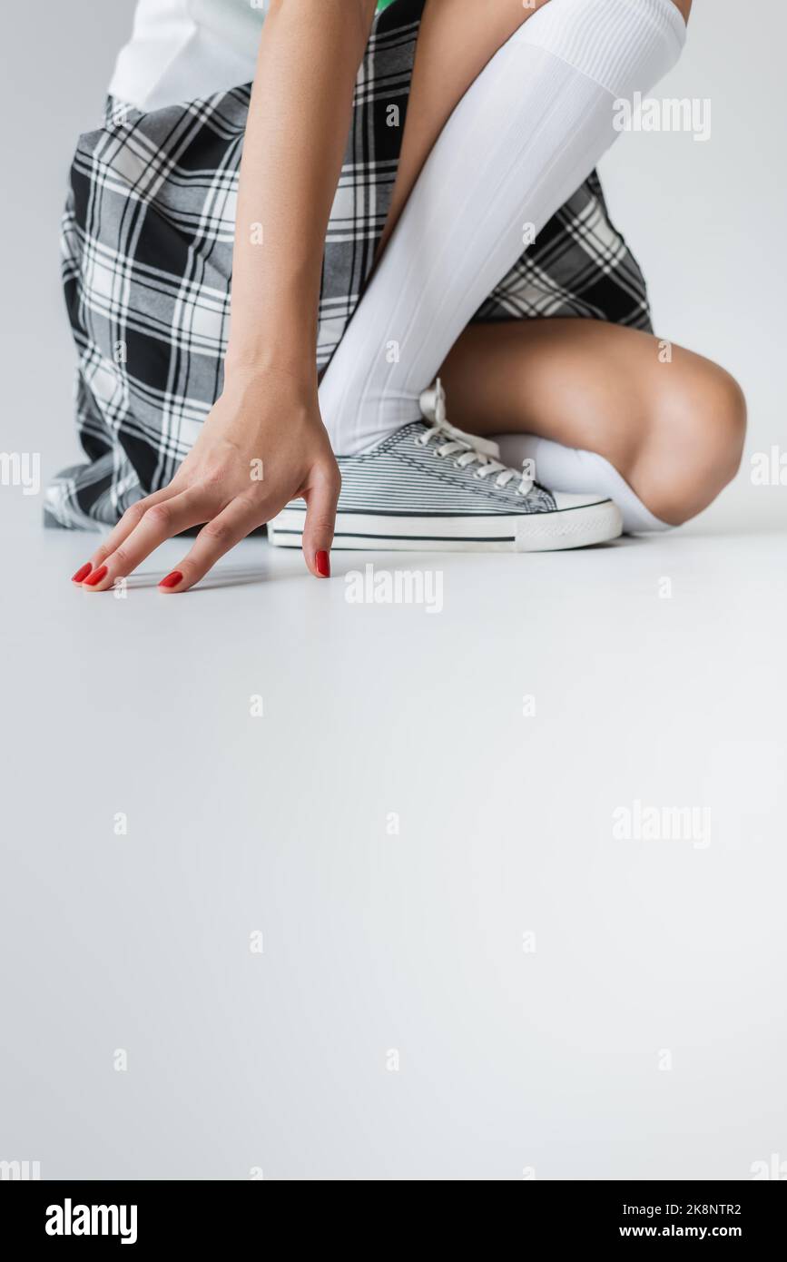 Cropped view of woman in plaid skirt and knee socks on grey background Stock Photo