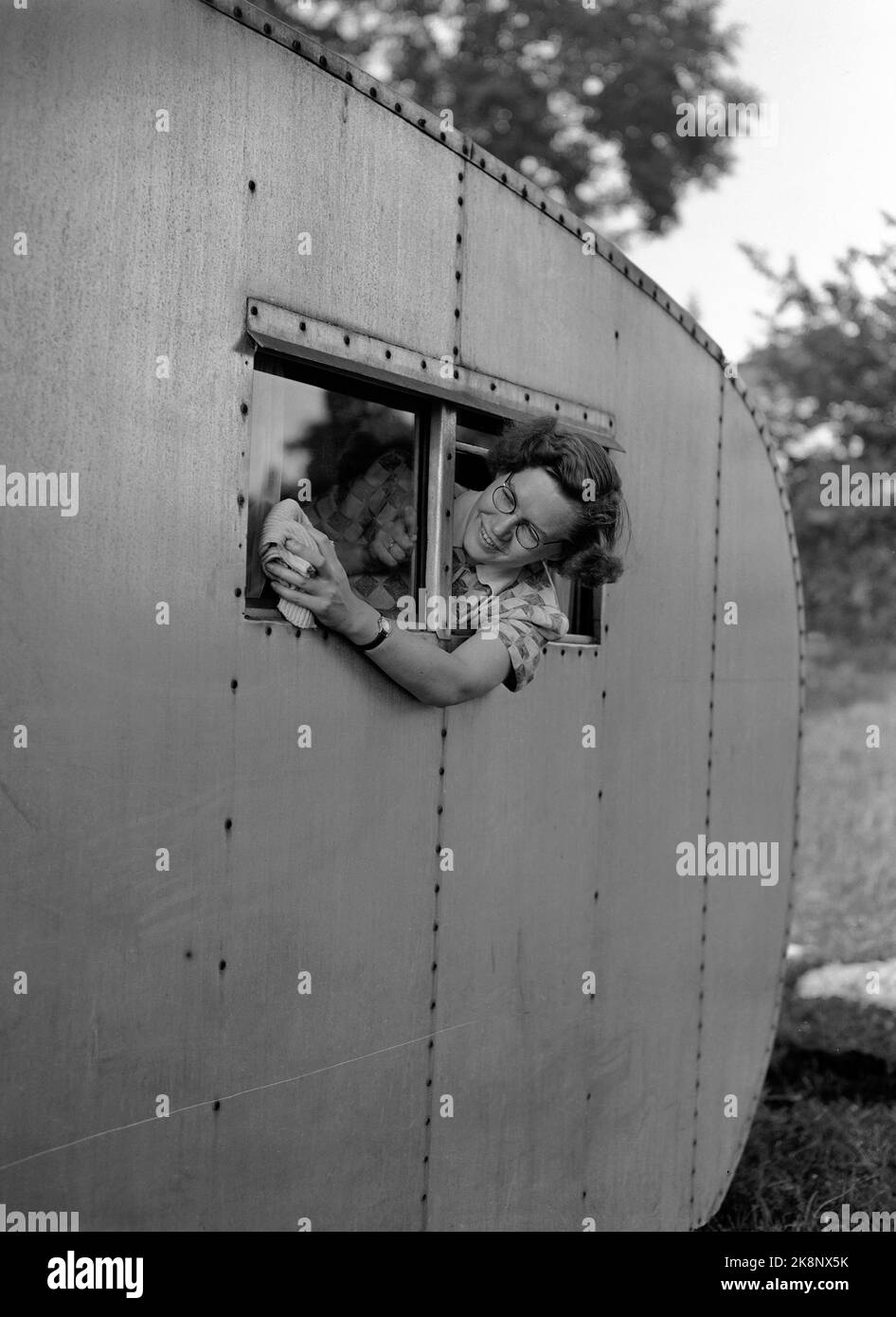 HUK 19530612 Camping at Huk. Holidays in a caravan does not always mean total relaxation for the housewife. Here's the mother about to brush the caravan window. Photo: Jan Stage / NTB / NTB Stock Photo