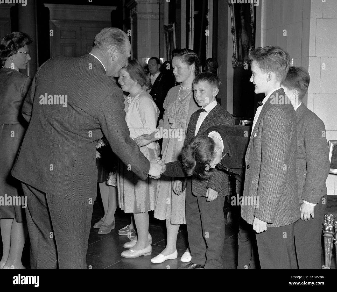 Oslo 19600420 Children from Sørøy in Finnmark on a school trip to Oslo, were invited to soft drinks and cakes at King Olav at the Castle. Here, Einar Jenssen greets King Olav with his deepest goat. TV. Princess Astrid who hosted the guests. Photo: NTB / NTB Stock Photo