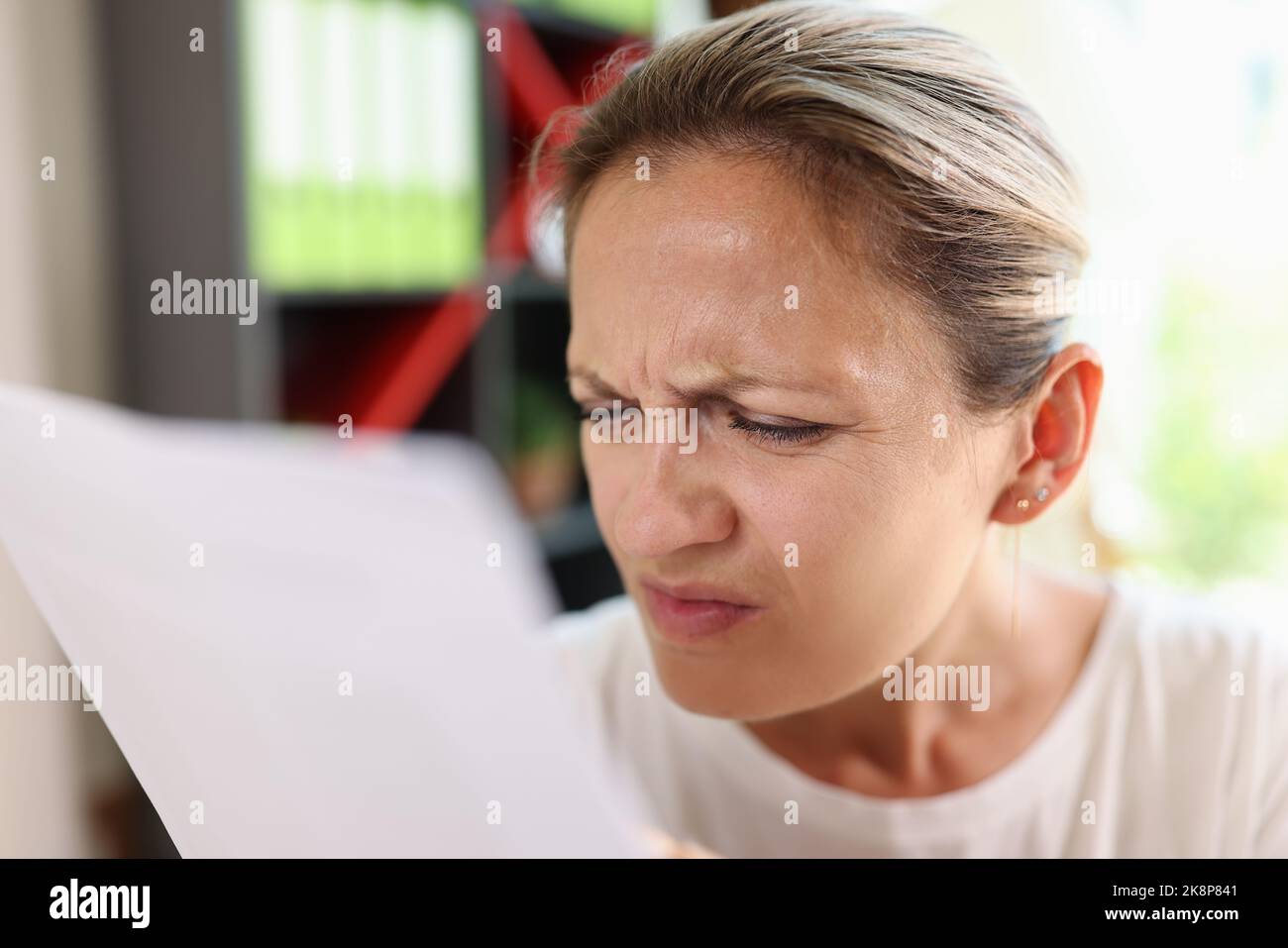 Focused woman trying read papers, squinting to see more clearly Stock Photo