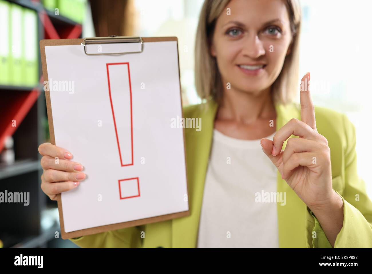 Woman holding clipboard with red exclamation point Stock Photo
