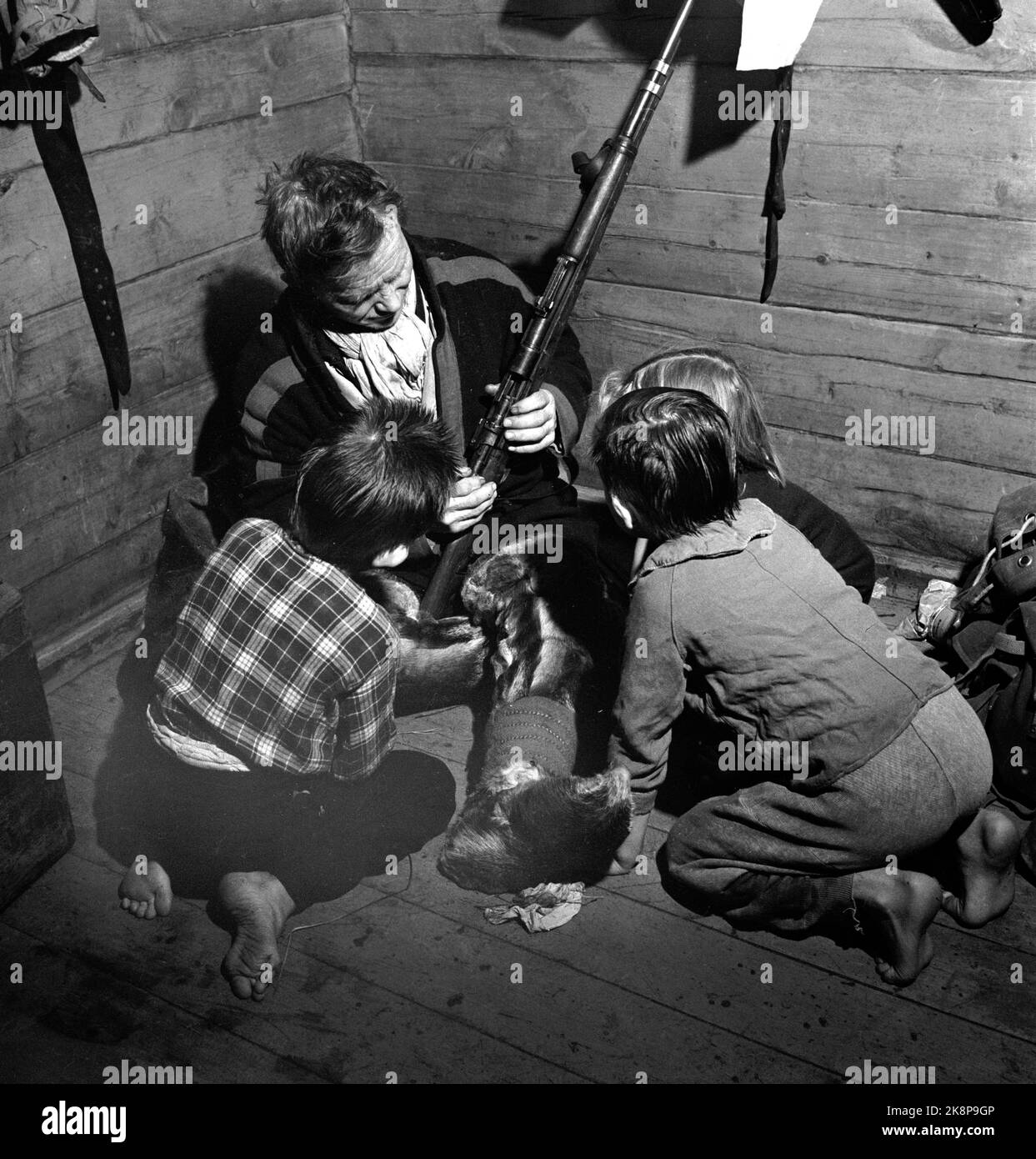 Finnmark in the winter of 1949. Extensive wolf hunting on Finnmarksvidda. The Ministry of Agriculture allocated money to hunt wolves in Finnmark after large flocks of reindeer had been damaged by wolves. The action used local and hired hunters as well as flights and belt cars. Young Same boys study the rifle of one of the hunters. Photo: Sverre A. Børretzen / Current / NTB Stock Photo