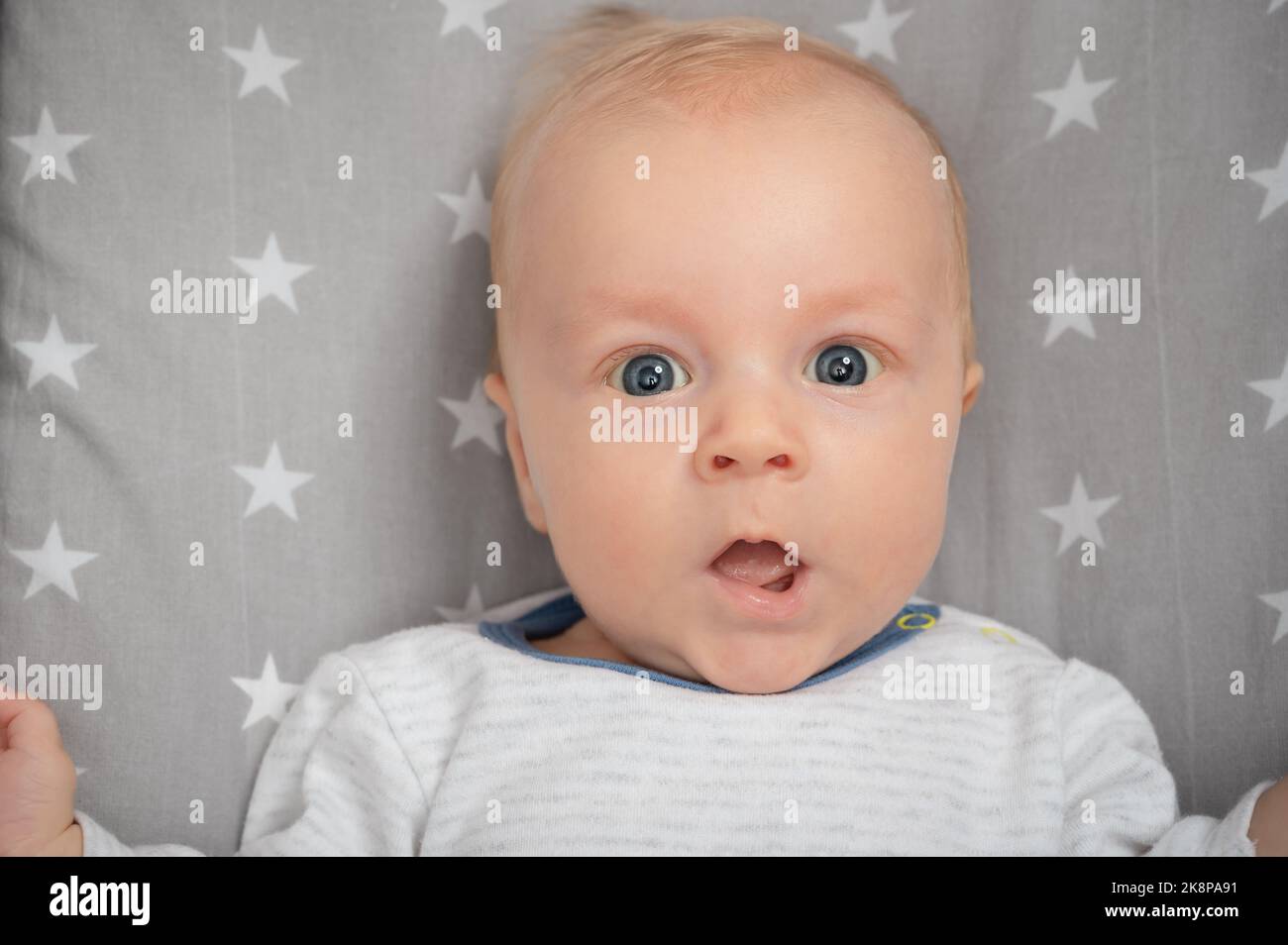 Portrait of surprised newborn baby with open mouth, closeup. Cut child