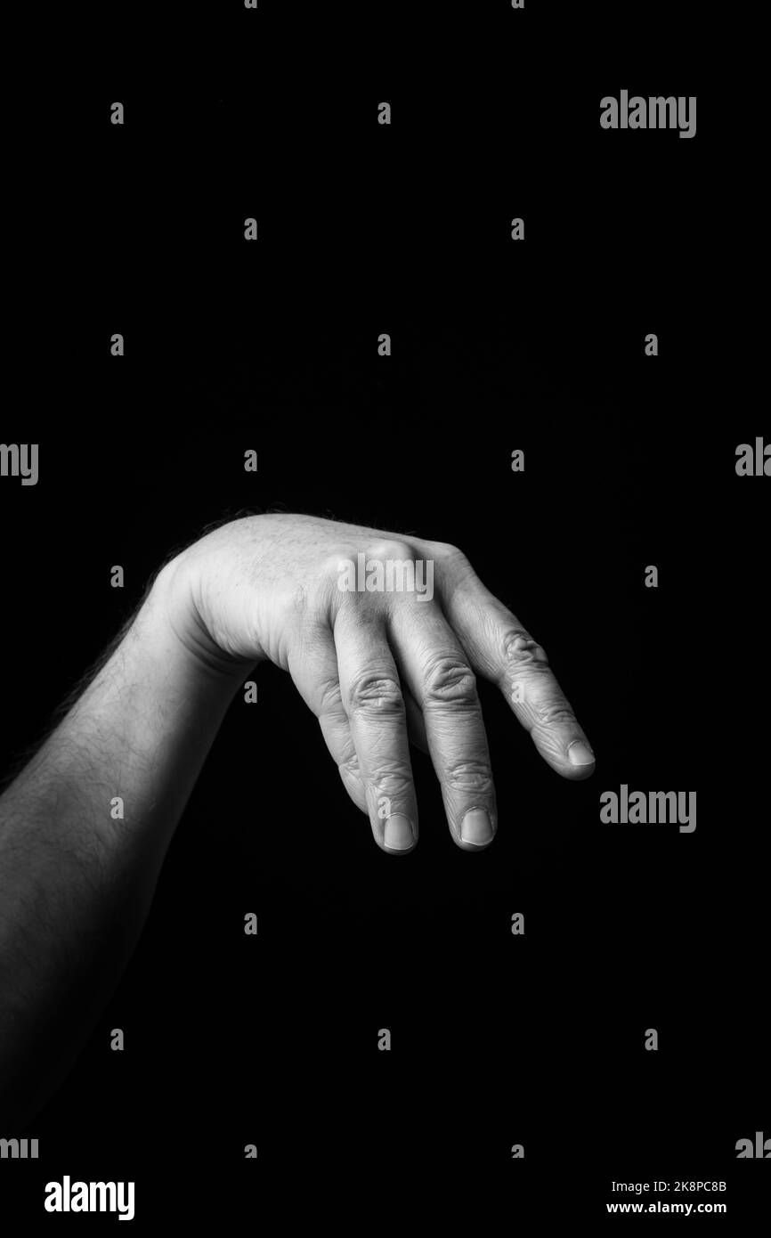 Dramatic black and white  image of a male hand fingerspelling the Japanese sign language letter 'MA' or 'ま, against a dark background with copy space Stock Photo