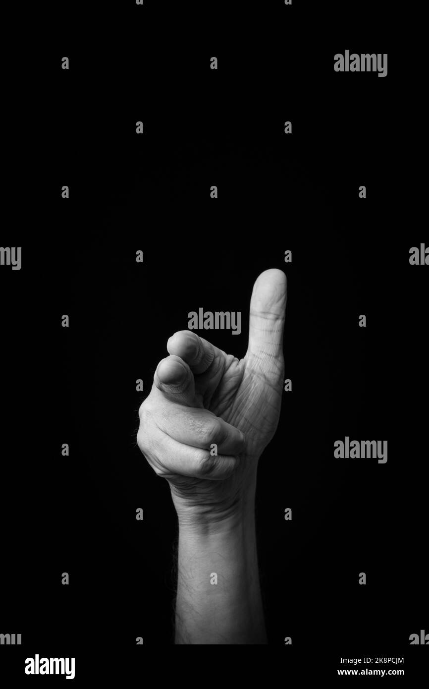 Dramatic black and white  image of a male hand fingerspelling the Japanese sign language letter 'HA' or 'は', against a dark background with copy space Stock Photo