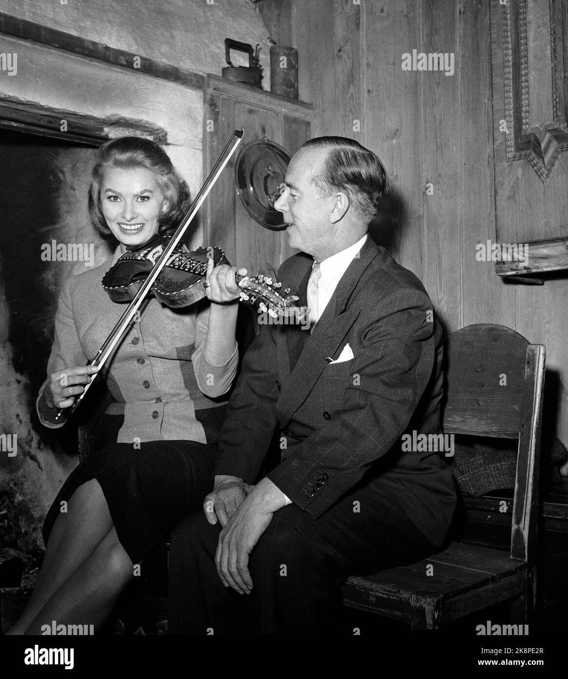 Oslo.19551208. Film actor Sophia Loren visits Norway. Here with actor Alfred Maurstad, who played harding fiddle for the diva at the Folk Museum. Afterwards, Sophia got a try, and the famous smile was loose! Photo NTB / NTB Stock Photo