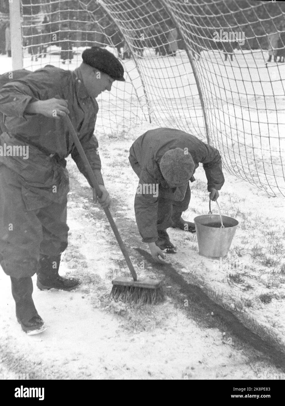 Oslo 19471115. Football in snowy weather at Bislett. The football match between Dynamo and Skeid was played on winter. Before and during the match it snowed tightly, and the grass mat was white and hard. 32,000 spectators are a record at Bislett. In the fresh snow, white sidelines are not useful. Both before and during the break between the laps, the track people sprinkle red tennis court flour on the lines to mark them. Photo: Current / NTB Stock Photo