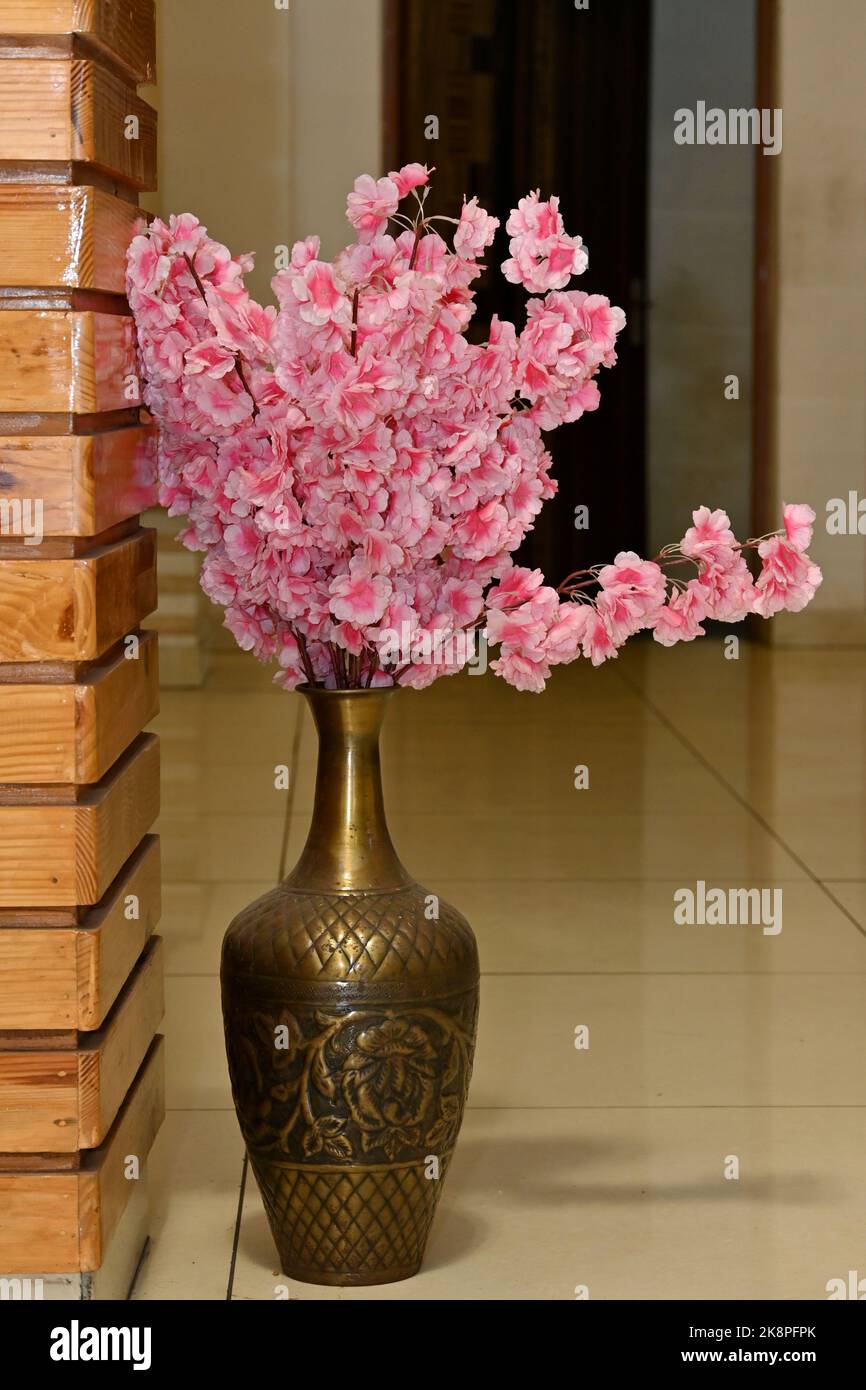 A vertical shot of a bronze vase with pink flowers Stock Photo