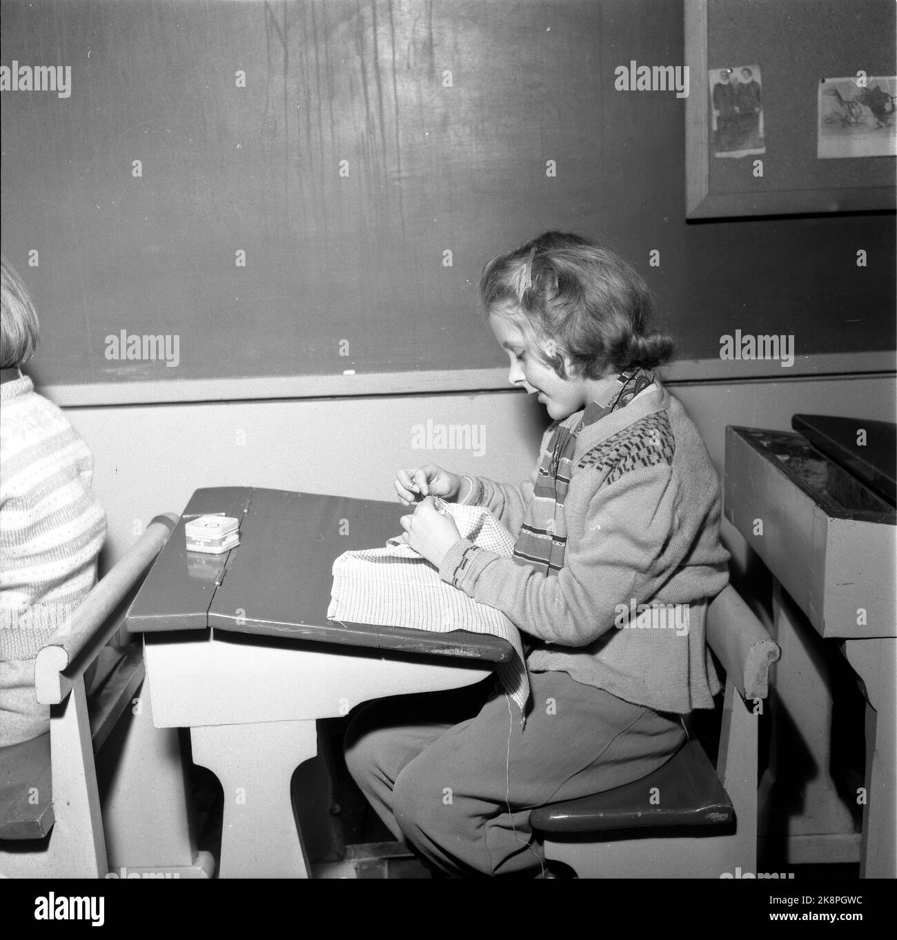 Oslo February 1955. Ruseløkka school. Handicraft, stitch in a school class: pure girl class at primary school. The girls sew small tablecloths in the classroom. Old desk of wood with lid. Photo: NTB / NTB Stock Photo
