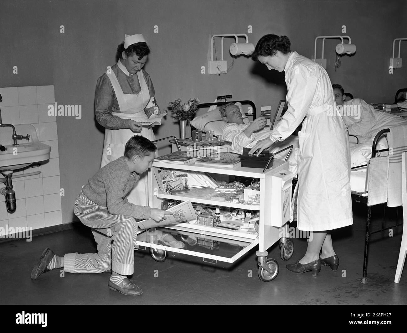 Oslo 19521204 In 1948, the Norwegian Red Cross took the initiative for training patient friends, volunteers who could visit lonely in hospitals or in the homes. The scheme was put into life in 1949. Here comes the patient friend with a trolley from which patients can supply themselves. Photo: NTB / NTB Stock Photo