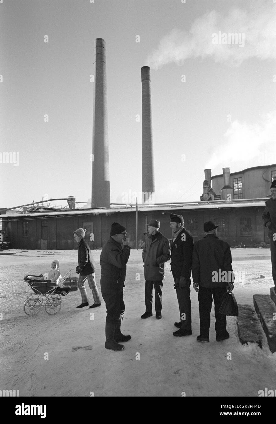 Vestfossen 19701212 The wheels are on Vestfossen. The layoffs at Vestfos Cellulose Factory came as a shock to the employees, as did the bankruptcy. Poor treatment of the employees. Environmental images from the last working days before the company closed its doors. Clusters of workers stand outside the factory and discuss the situation. Woman with stroller in the background. Photo; Sverre A. Børretzen / Current / NTB Stock Photo