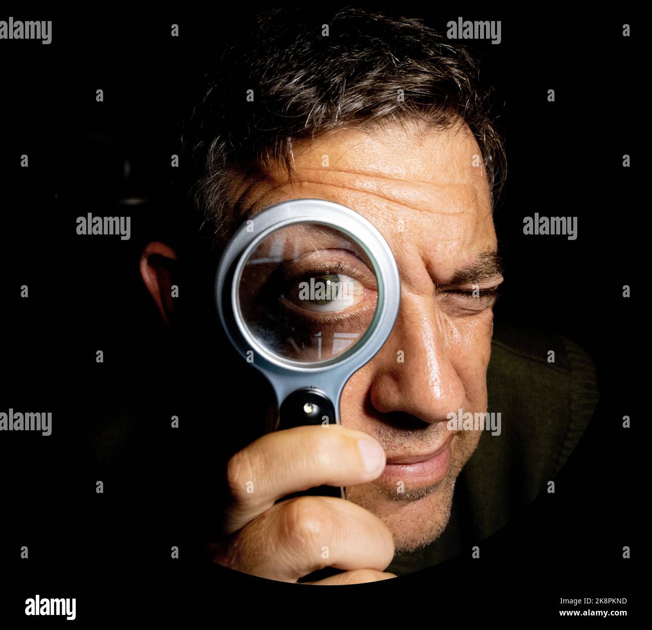 A comic portrait of a man holding a magnifying glass in front of his eye Stock Photo