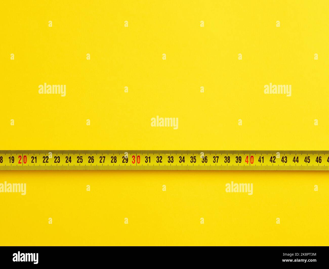 To evaluate or measure the size concept. Tape measure on yellow background with copy space. Stock Photo
