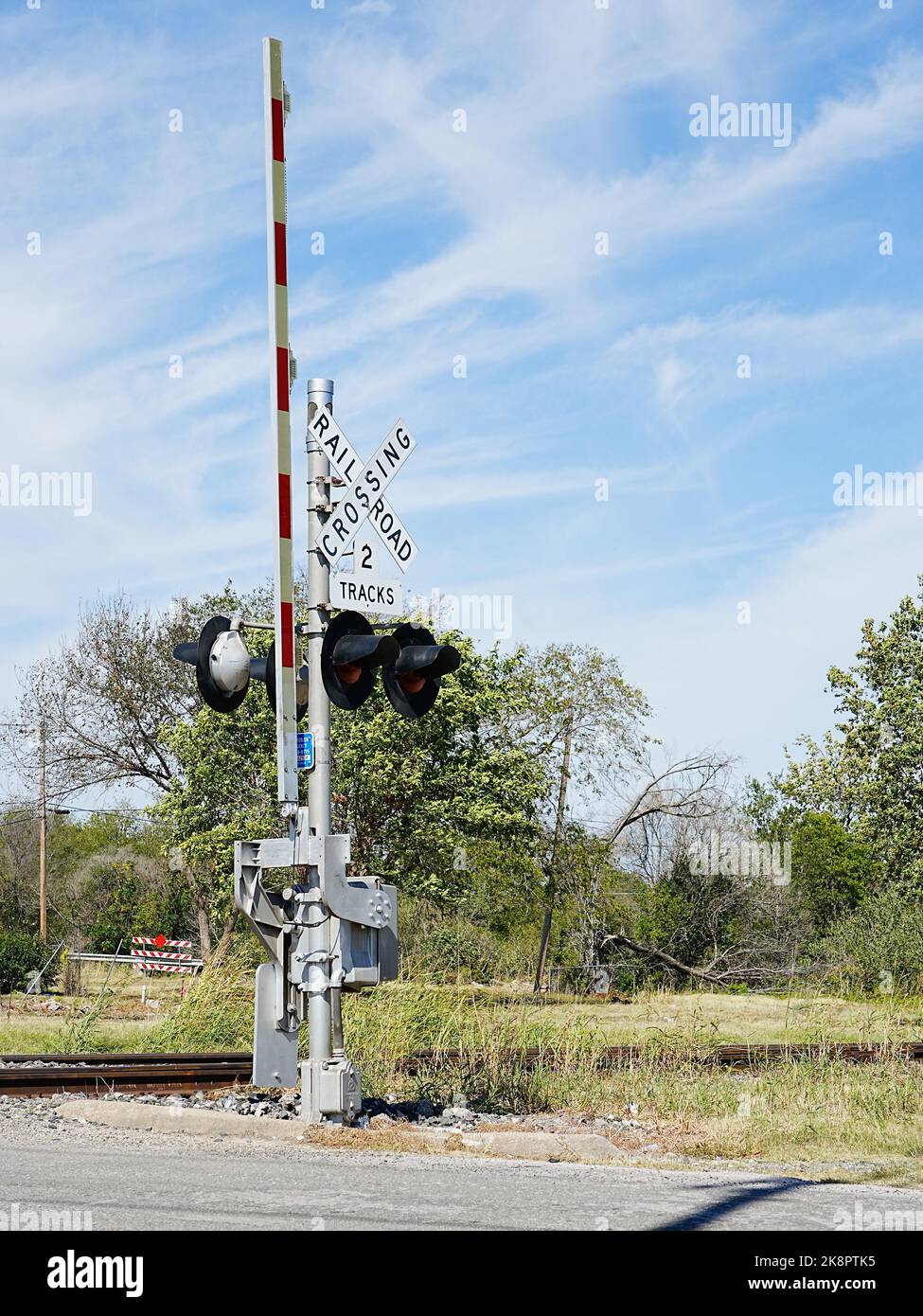 Railroad street grade crossing warning signal and gate. Flashing lights and lowering of the gate arm warns drivers of approaching train. Stock Photo
