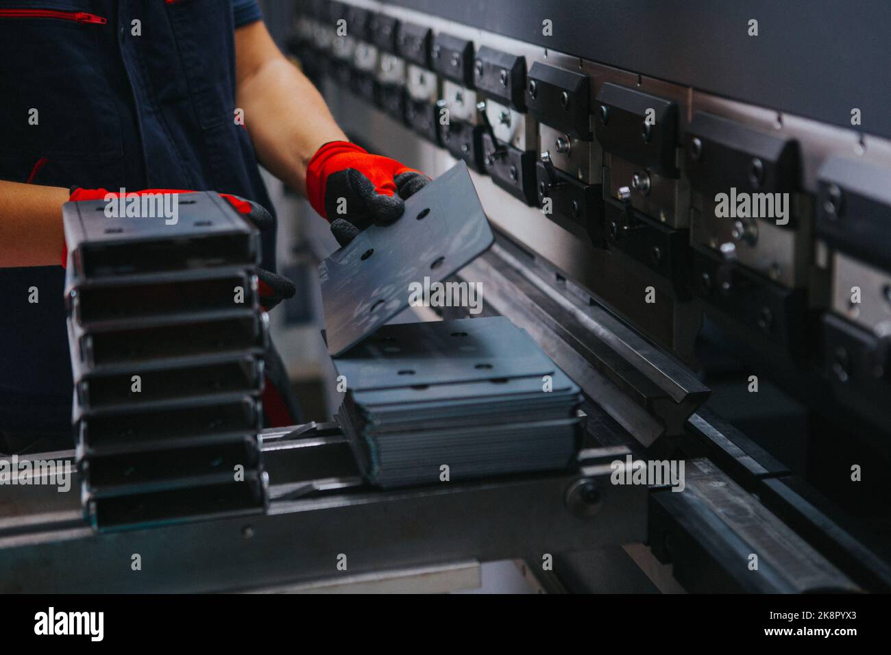 A factory worker arranges metal parts on top of each other, closeup